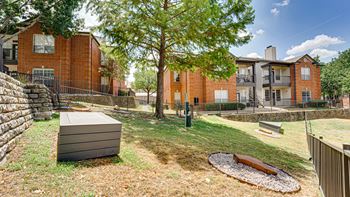 A backyard with a brown hot tub and a tree.